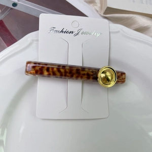 Detail of tortoise shell acetate hair clip with gold metal disc on a display card
