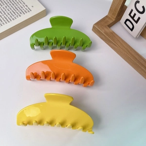 Three large colorful hair claws in bright green, orange, and yellow for women hair styling