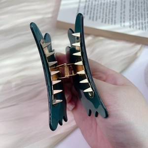 Detail view of dark green acetate hair claw with durable gold metal spring and teeth