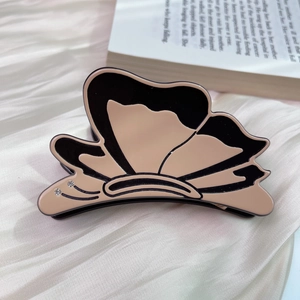 Detail view of acetate butterfly hair claw with two rhinestones on beige satin fabric