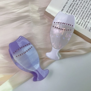 Elegant marble texture acetate hair claws with pink rhinestones set on a golden satin background