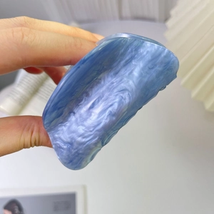 Primo piano di un fermaglio per capelli in acrilico blu marmorizzato tenuto in mano