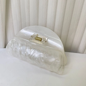 Dettaglio della molletta per capelli in acrilico bianco perla con trama effetto marmo