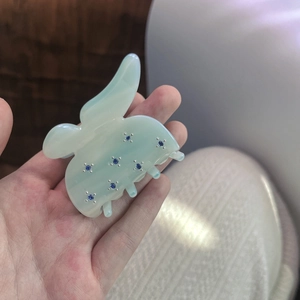 Elegant butterfly-shaped hair claw in teal marble resin with sparkling blue rhinestones