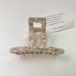 Detail view of marble pattern acetate hair claw clip with strong golden metal spring