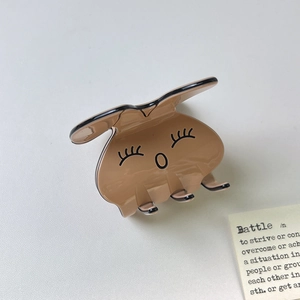 Détail d'une pince à cheveux lapin en acétate poli sur un fond de couleur neutre épuré