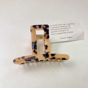 Detailed top view of a tortoise shell acetate hair claw with a gold metal spring