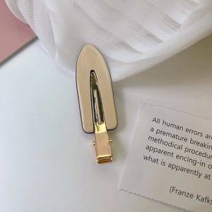 Nahaufnahme der cremefarbenen Acetat-Haarklammer mit goldenem Metallsockel auf Hintergrund
