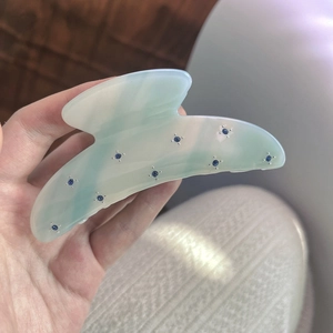 Detail showing mint green marble acetate hair claw clip with blue crystal embellishments
