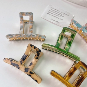 Flat lay of five large square acetate hair claws in various marble and tortoiseshell patterns