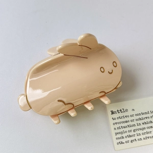 Détail d'une pince à cheveux lapin en résine crème montrant la finition lisse et brillante