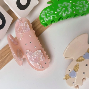 Detail of acetate hair claws featuring embossed hearts, clover and rhinestone accents