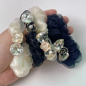 Detail of camellia hair scrunchies with rhinestones and pearls in black and cream organza
