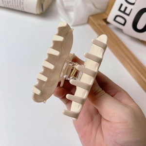 Close-up of a cream acetate hair claw clip with sturdy metal spring for thick hair