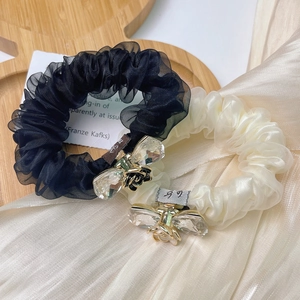 Elegant organza scrunchies in black and beige with crystal bee accents on satin background