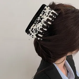 Macro detail of the square marble patterned acetate hair claw clip on deep brown hair