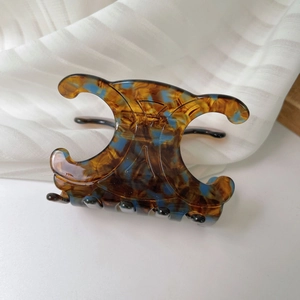 Detailed close-up of tortoise shell hair claw clip with blue patches in Triomphe design