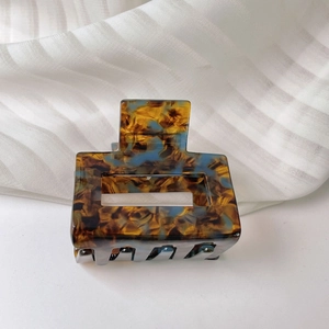 Macro view of rectangular amber and blue acetate hair claw clip with cutout geometry