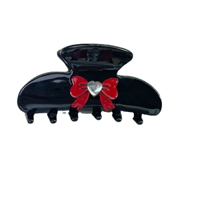 Chic black acetate hair claw with a red bow and crystal heart center on white background