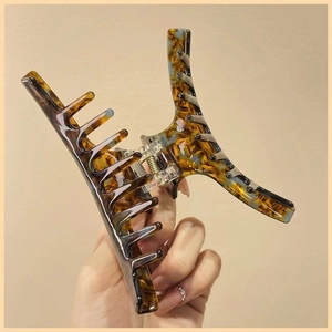 Close-up of a large tortoise shell hair claw clip with amber texture and metal spring detail