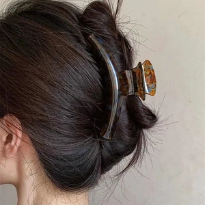 Detailed view of large tortoiseshell hair claw clip securing a full bun on dark hair