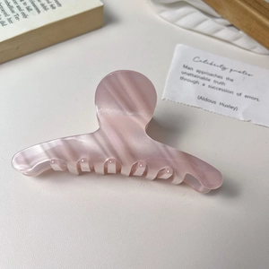 Close-up of pink acetate hair claw clip with marble texture on minimalist background
