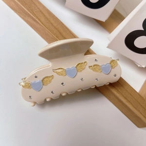 Chic cream acetate claw clip featuring blue hearts with golden glitter wings and crystals