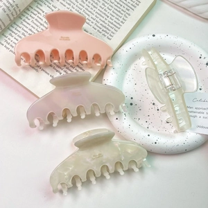 Close-up of four assorted acetate hair claws in pastel pink and pearly white finishes