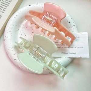 Close-up of pink and green acetate hair claws in a ceramic dish for French elegant styling