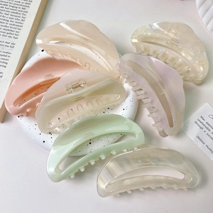 Détail de pinces à cheveux en acétate ajouré aux tons pastels sur une assiette blanche