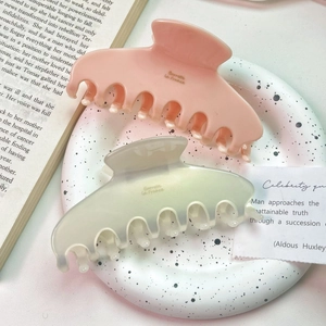 Elegant pink and light green acetate shark hair clips on a decorative marble tray