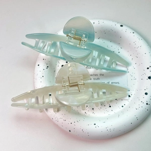 Detail view of 13cm oversized acetate hair claw clips in light blue and creamy white finishes