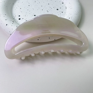 Détail macro d'une pince à cheveux en acétate nacré avec logo doré France Handmade