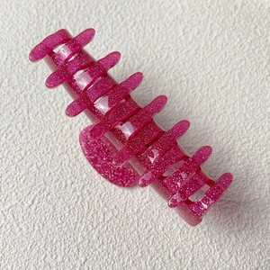 Gros plan sur une pince à cheveux rose vif pailletée en acrylique avec dents solides