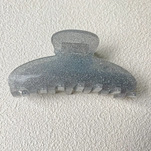 Détail macro d'une pince à cheveux en acrylique argenté pailleté avec dents entrelacées