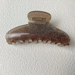 Détails macro de la pince à cheveux en acrylique marron foncé pailleté au design incurvé