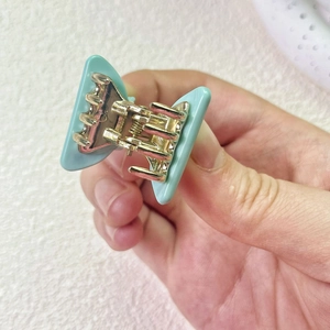 Detailed macro view of the butterfly-shaped hair claw clip with blue wings and gold metal