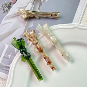 Chic acetate bow hair clips in marble and green tones displayed on a white plate