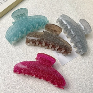 Pinces à cheveux en acrylique pailleté en quatre couleurs sur fond texturé blanc