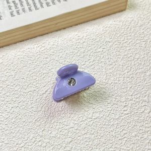 Detail of lavender acetate hair claw with rhinestone on white textured background