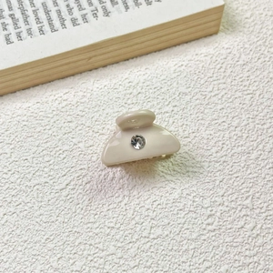 Close-up of beige acetate hair claw clip featuring a sparkling center rhinestone detail