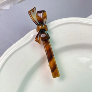 Detail of tortoise shell acetate bow hair clip showing textured material and glossy finish