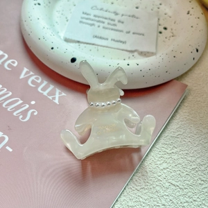 Vue détaillée de la pince à cheveux lapin en acétate crème avec perles et texte doré