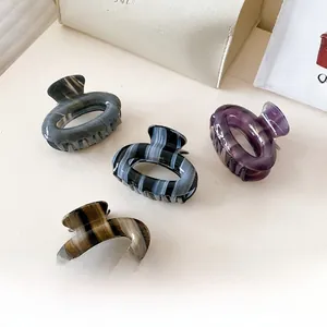 Macro detail of striped acetate hair claws with premium marble and amber textures