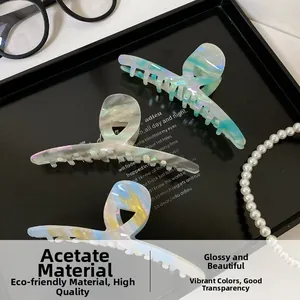 Three acetate shark hair claws with iridescent colorful textures in a stylish setting