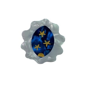 Artistic ocean-themed acetate hair clip with golden sea stars on deep blue background