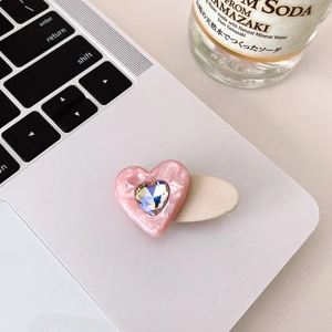Pink heart-shaped acetate hair clip with sparkling rhinestone on a laptop surface