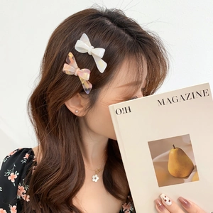 Sweet acetate bow hair clips set with glossy white and marble yellow finishes on model