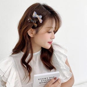 Elegant bow-shaped acetate hair clip with tortoiseshell and pearl finish on model
