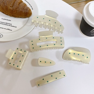 Detailed set of cream acetate hair clips with green rhinestones in a lifestyle setting